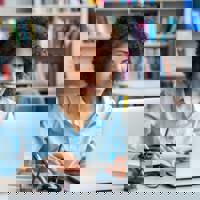 woman with books looking at laptop