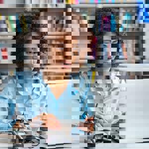 woman with books looking at laptop